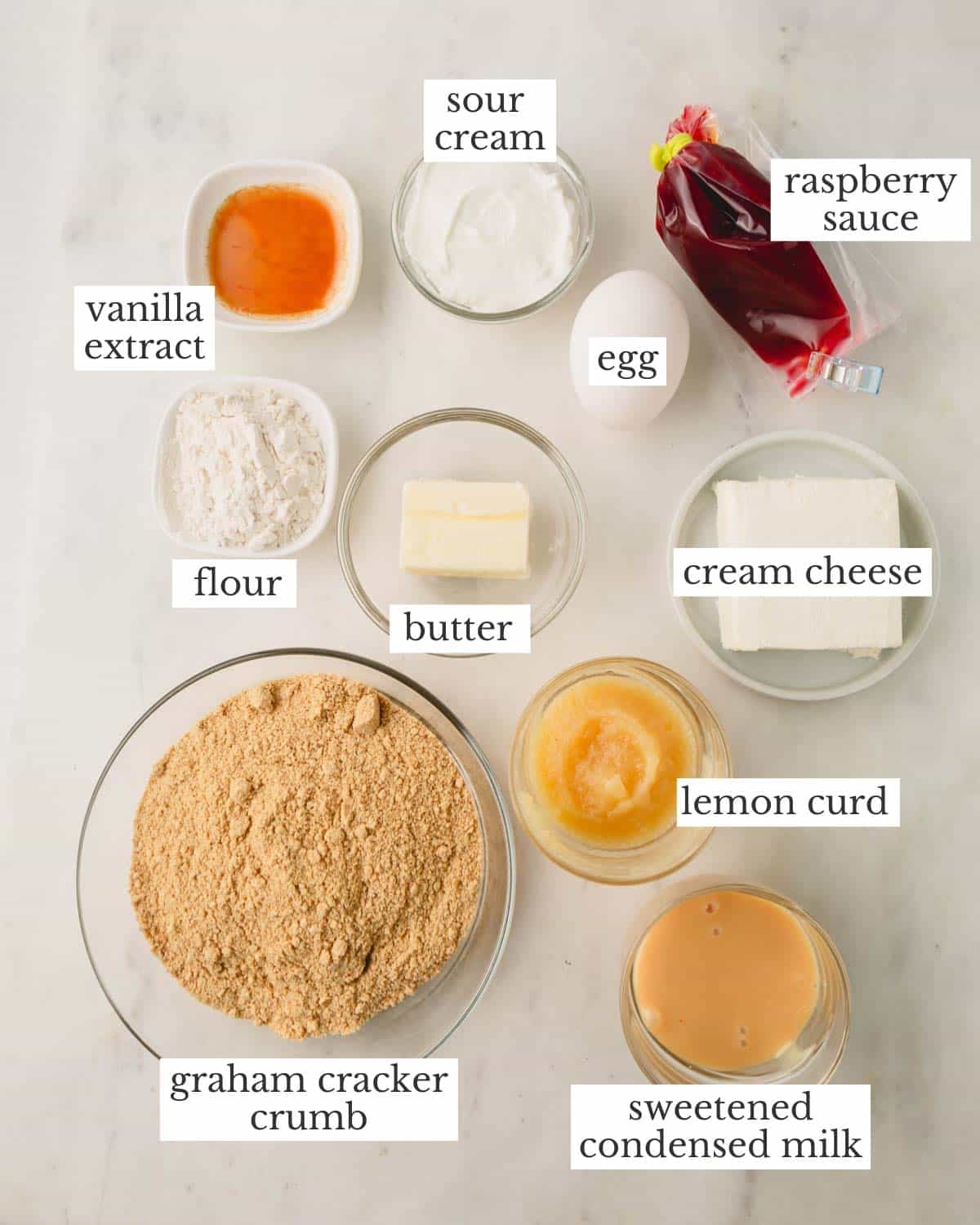 Ingredients to make lemon raspberry cheesecake bars with a graham cracker crust.