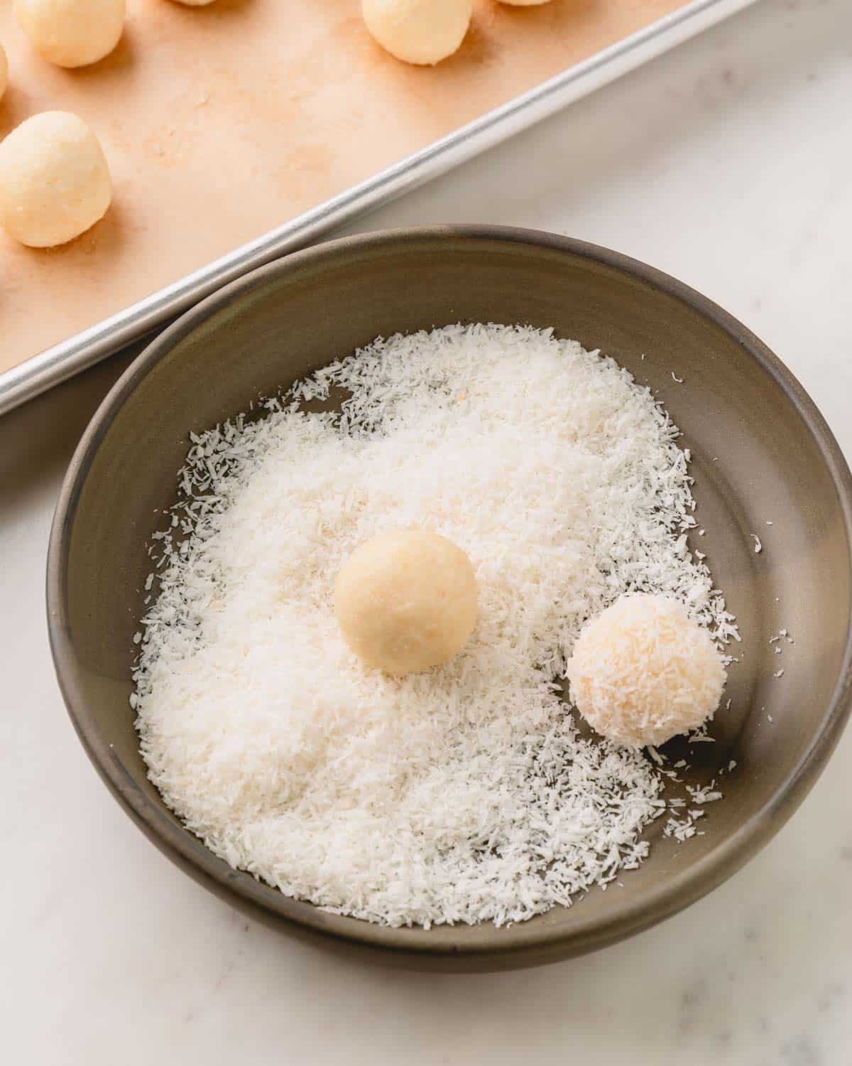 Coconut balls in a bowl of desiccated coconut.