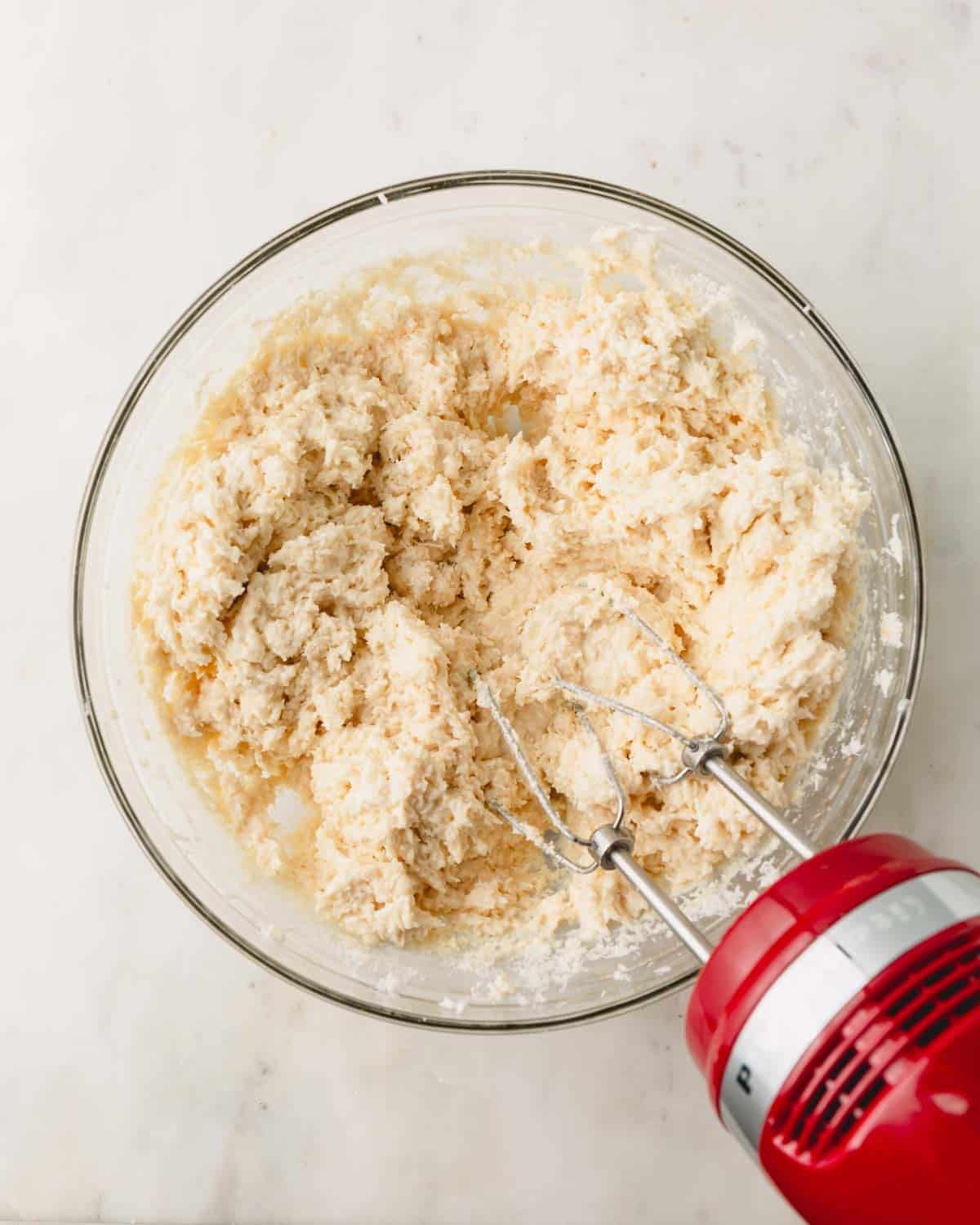 Coconut ball dough in a bowl with a hand mixer sticking out.