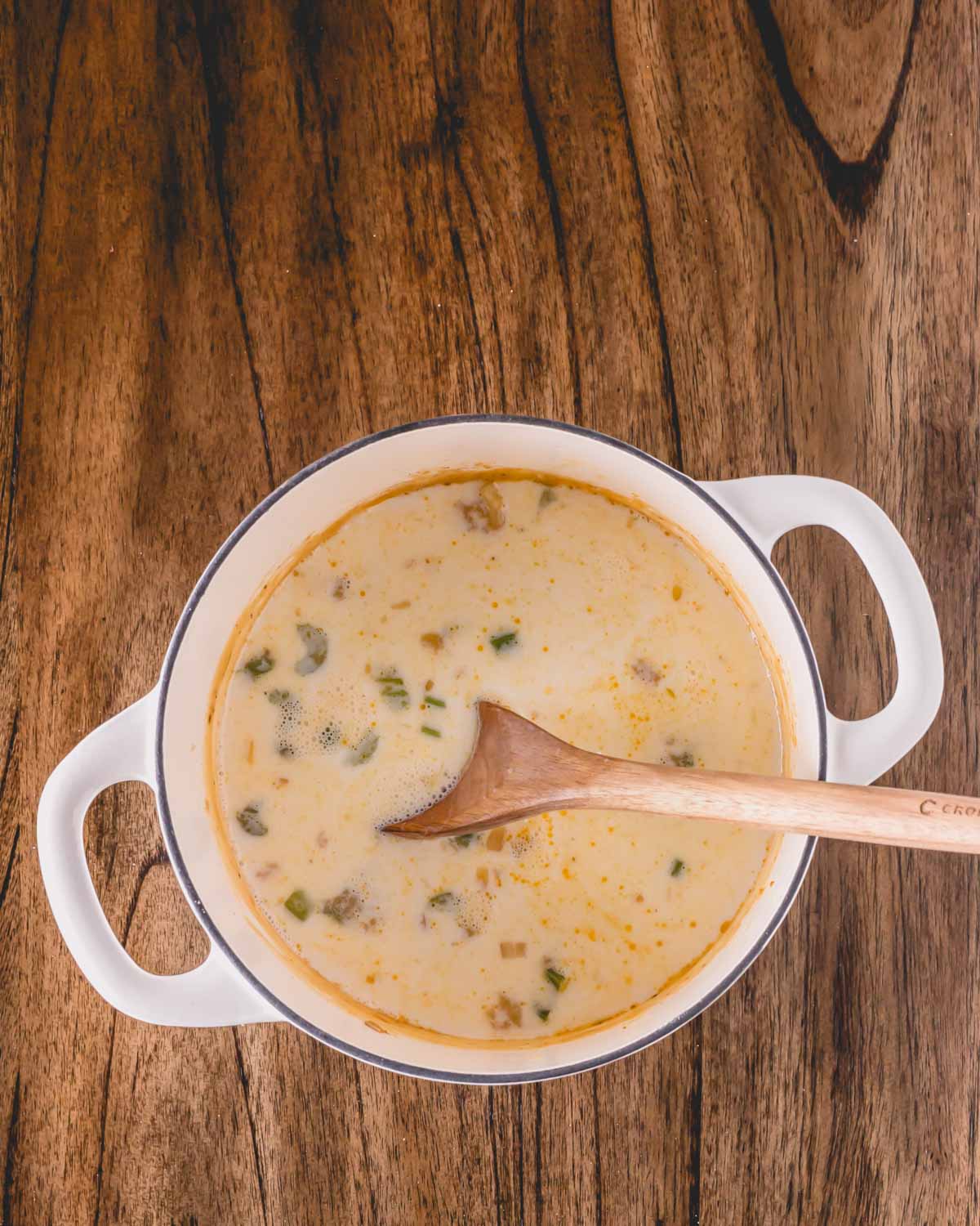 A pot of oyster stew with potatoes, a wooden spoon sticking out.