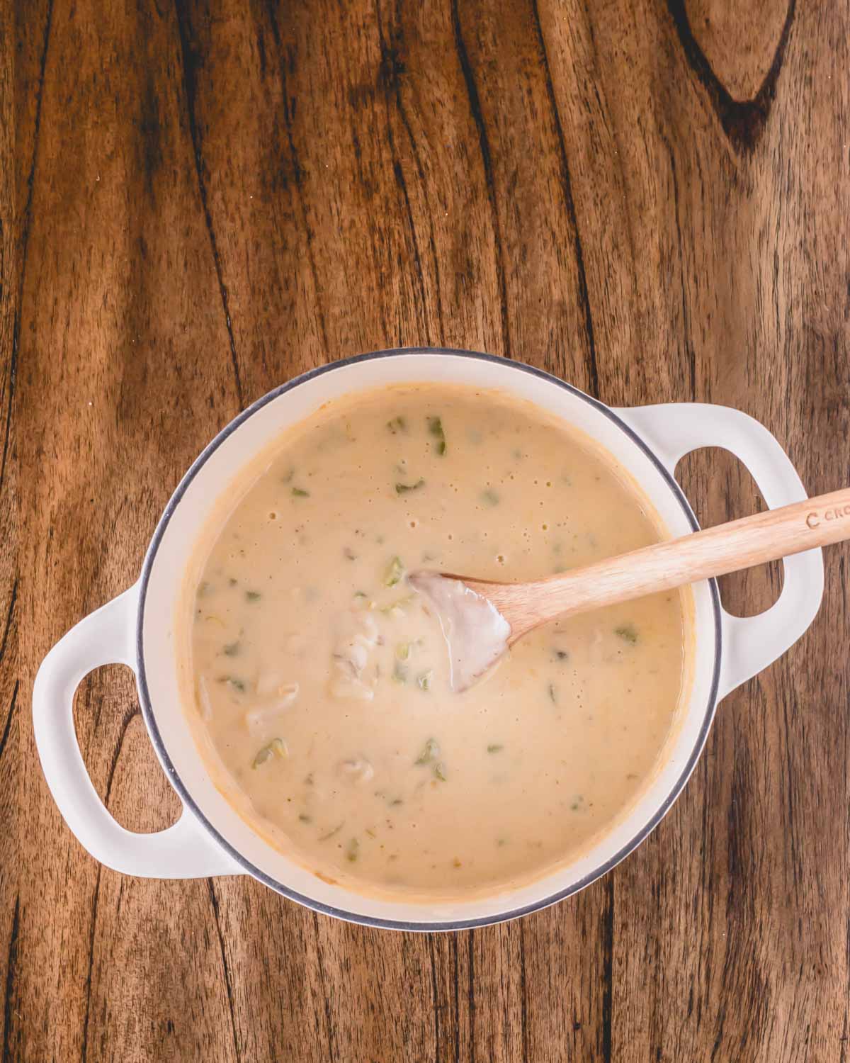 A pot of oyster stew with a wooden spoon sticking out.
