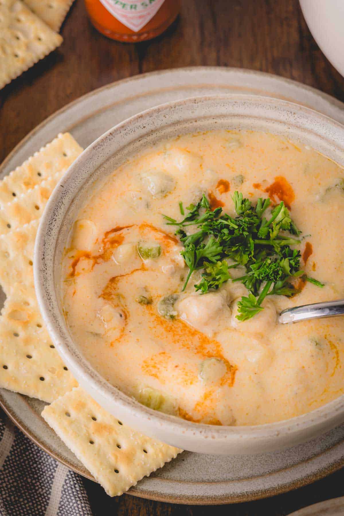 A bowl of oyster stew surrounded by crackers.