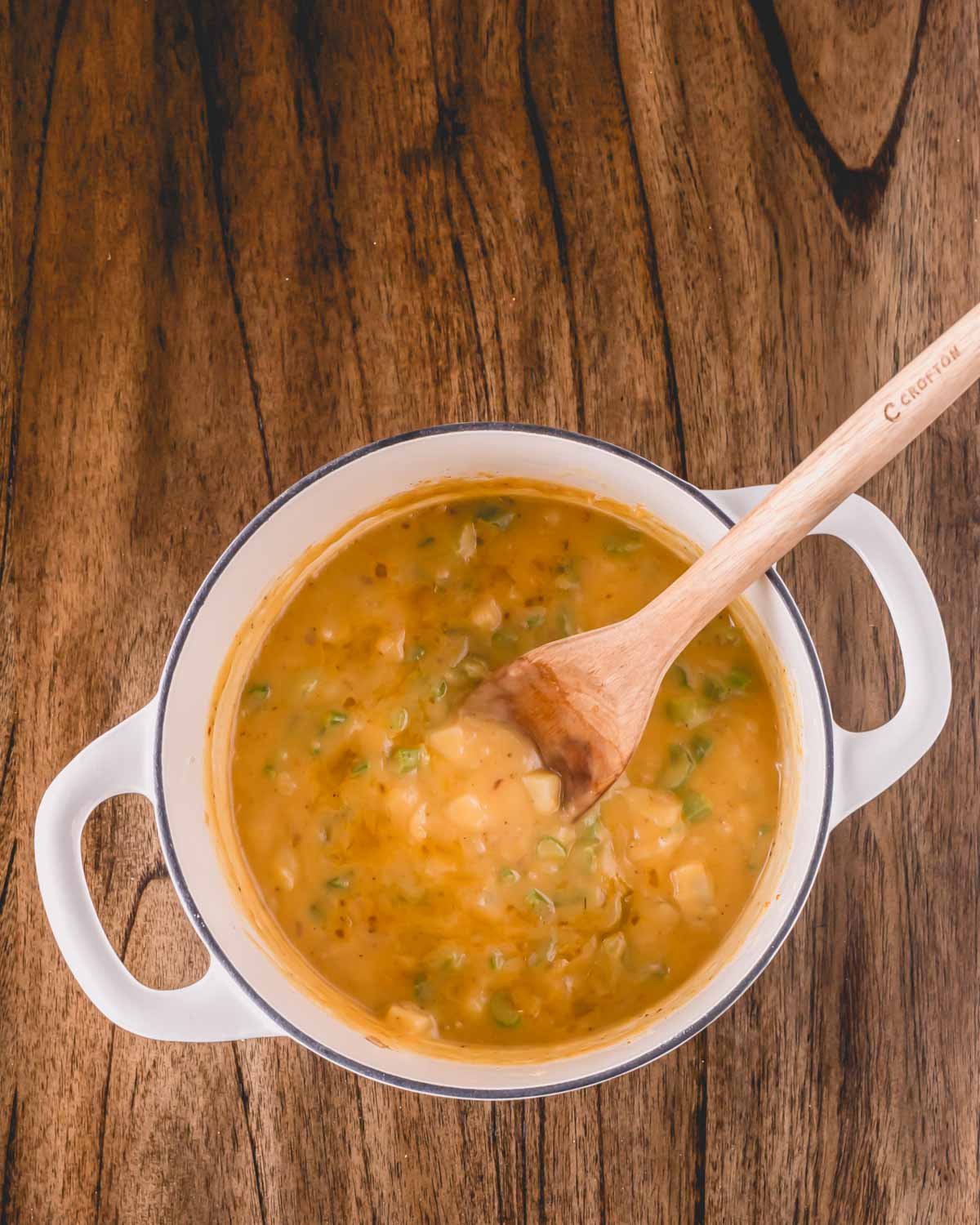 Oyster stew cooking in a pot, a wooden spoon sticking out.
