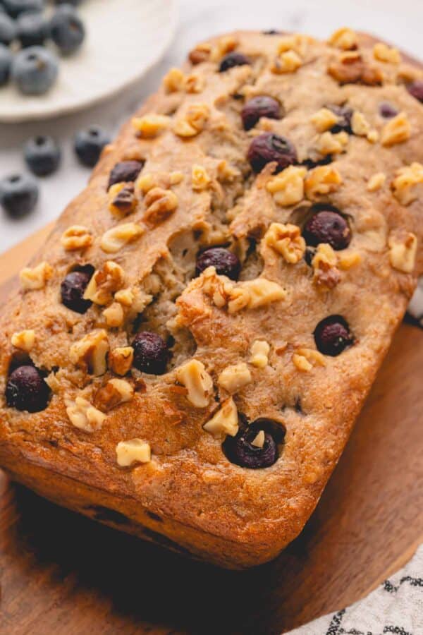 A loaf of blueberry banana bread topped with blueberries and walnuts.