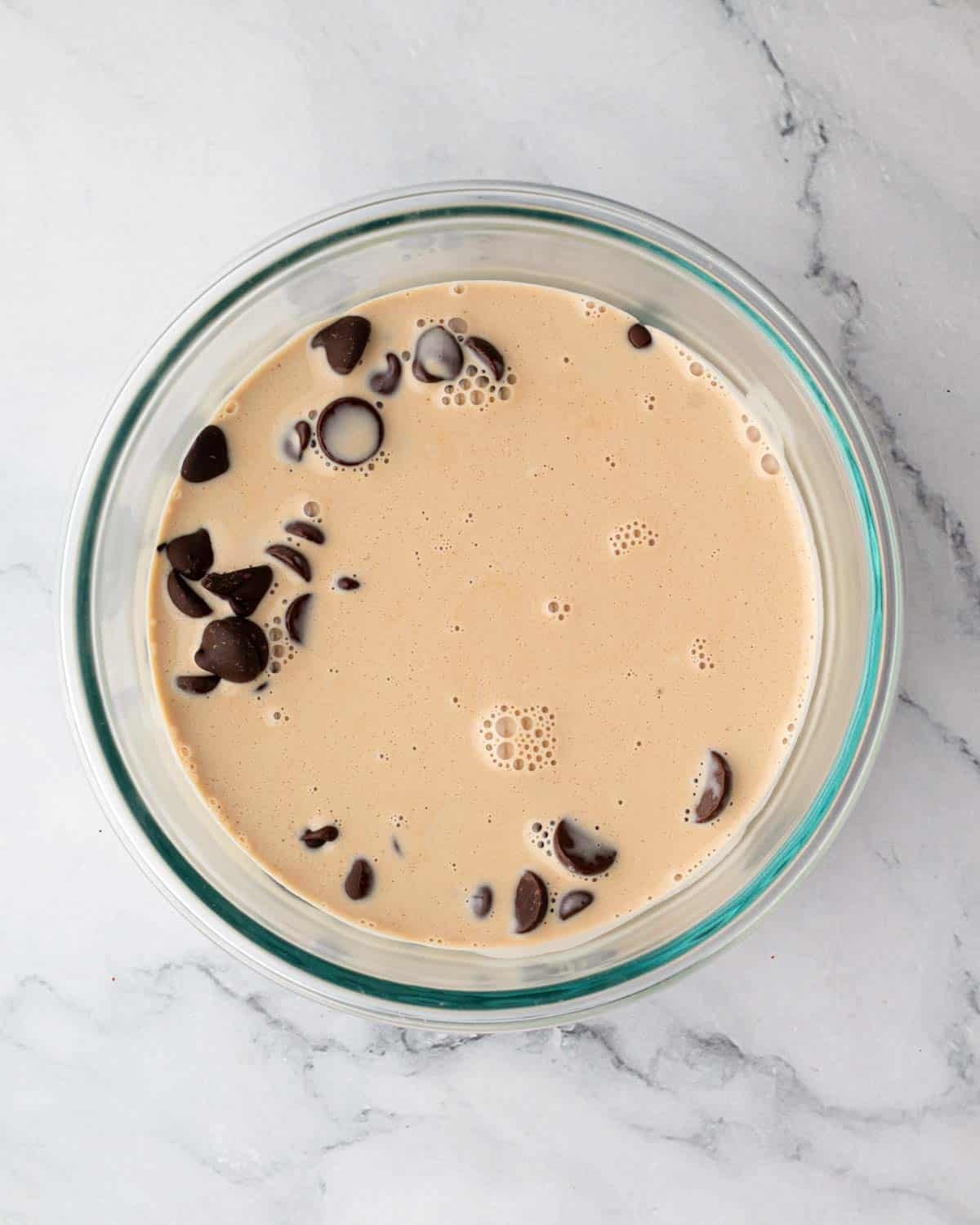 A bowl of chopped chocolate topped with heavy cream.