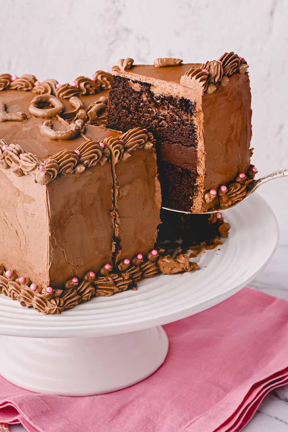 A slice of chocolate heart cake being lifted from a cake pan.