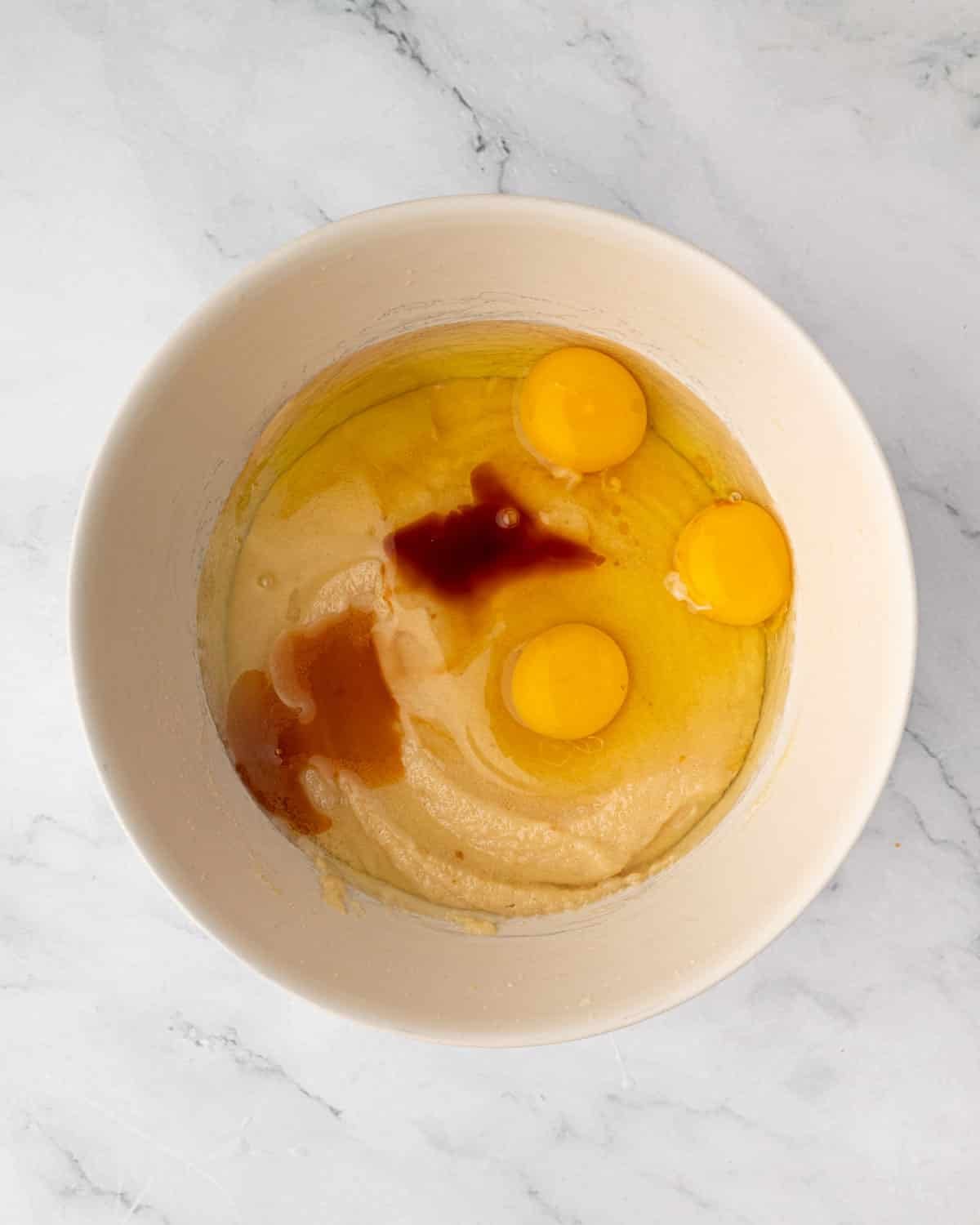 Eggs and vanilla being added to a bowl of red velvet brownie batter.