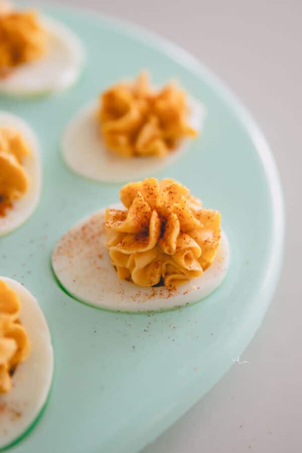 Close up image of curry deviled eggs on a blue platter.