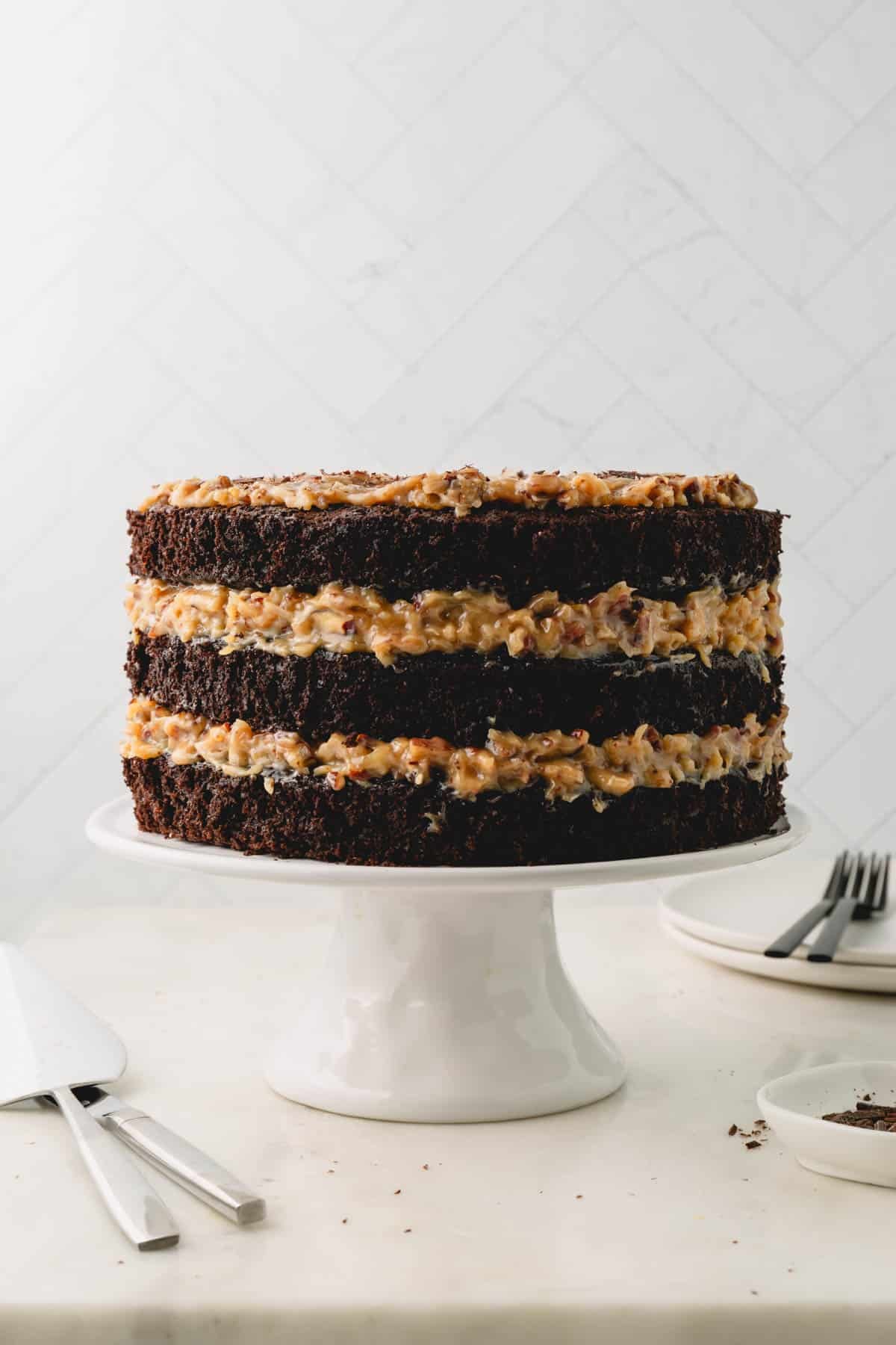 Three layer German chocolate cake on a white cake pedestal.