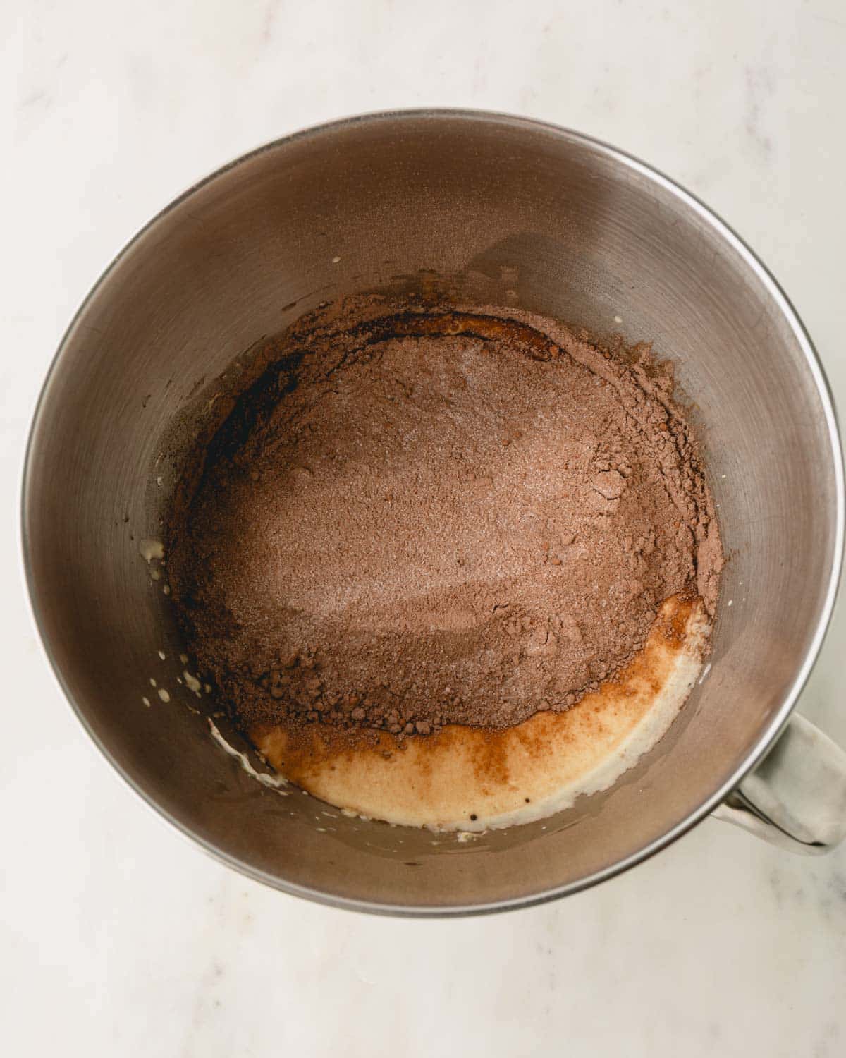 A metal bowl with dry and wet ingredients for German chocolate cake.