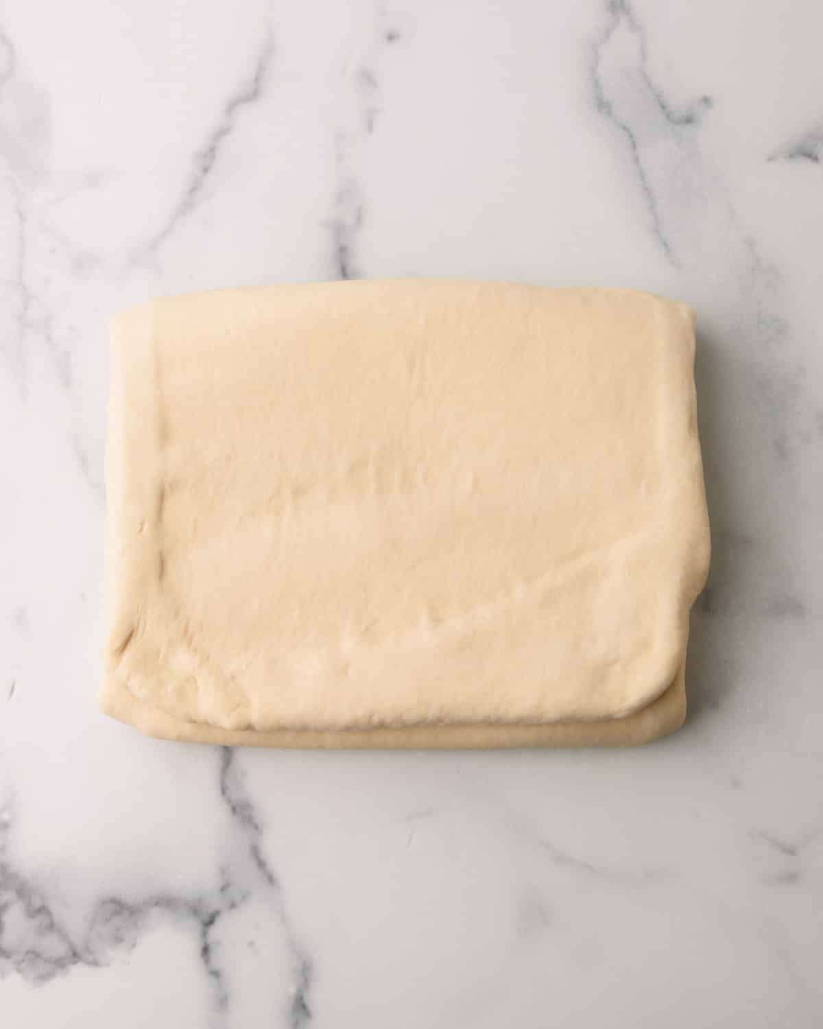 Croissant dough being folded into a letting which is called lamination.