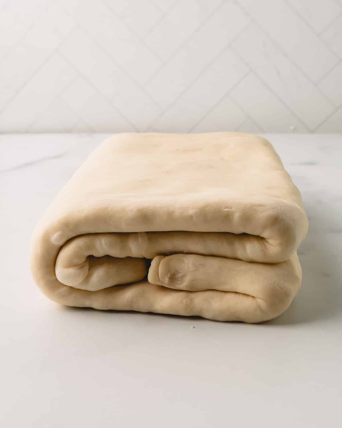 Side view of croissant dough being folded.