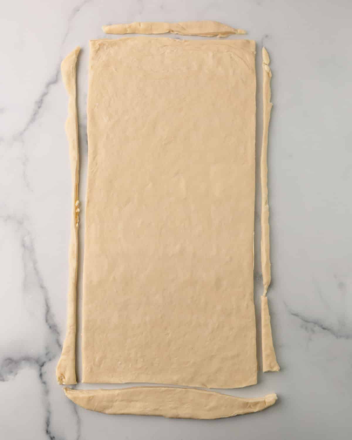 Trimming the sides of croissant dough rolled out.