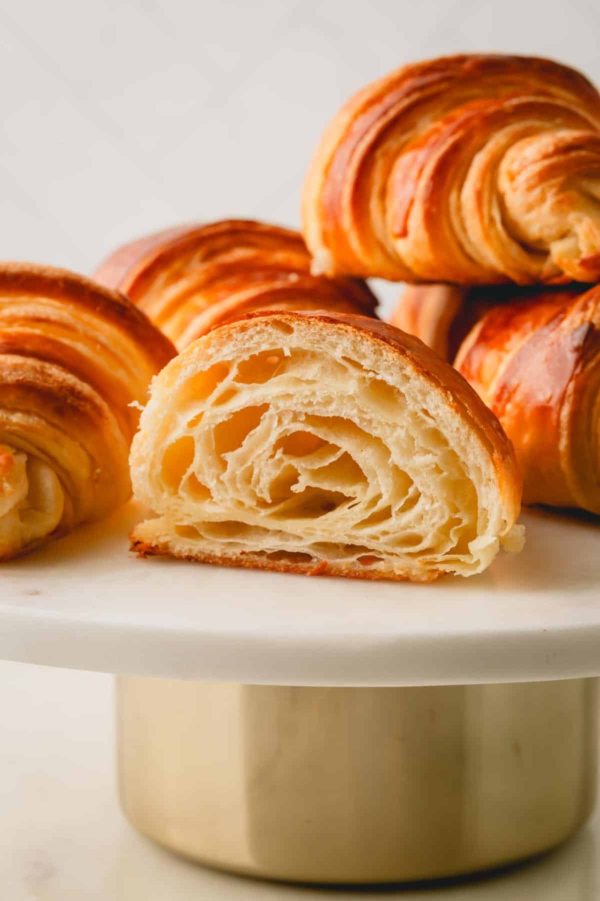 Side view of a cut croissant on a cake stand.
