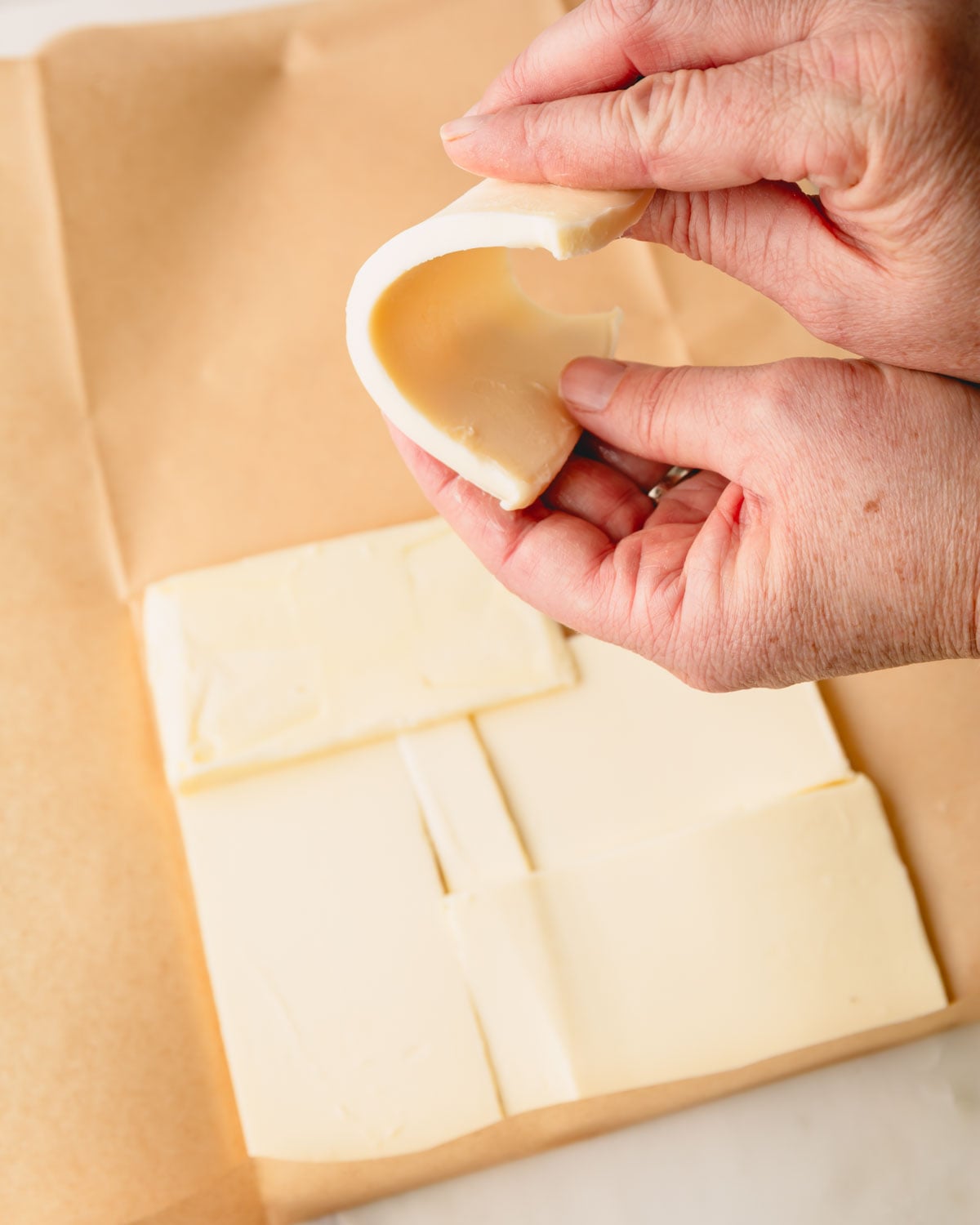 Hands shaping butter into a squre.