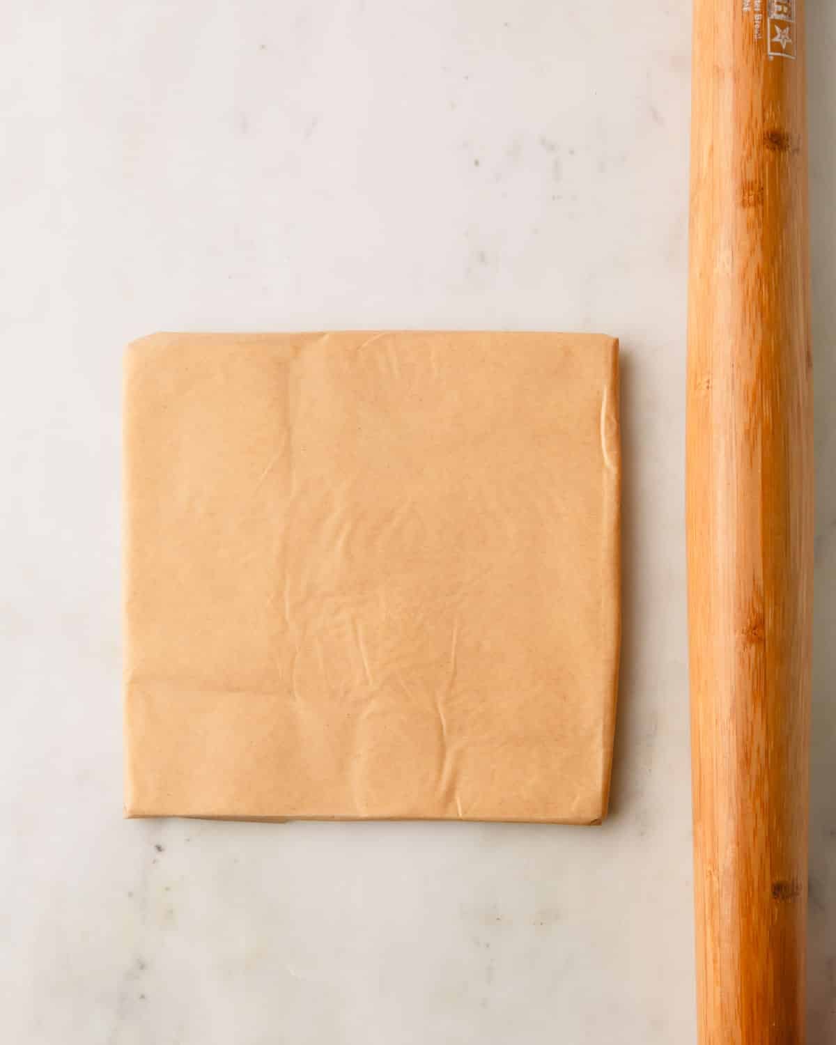 Rolling pin rolling butter into a square.