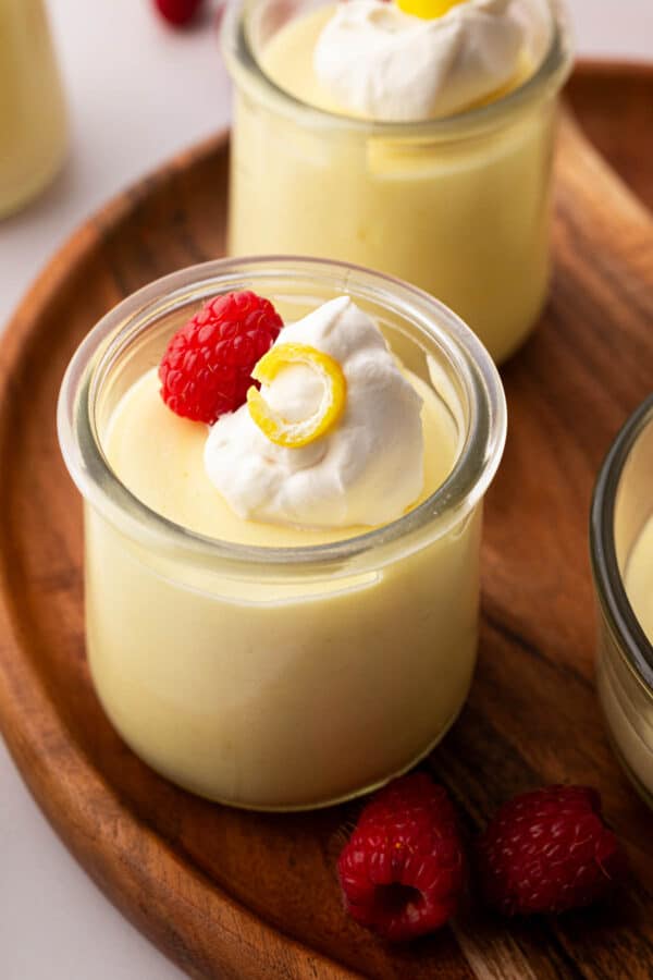 Lemon mousse in a small glass jar on a wooden board.