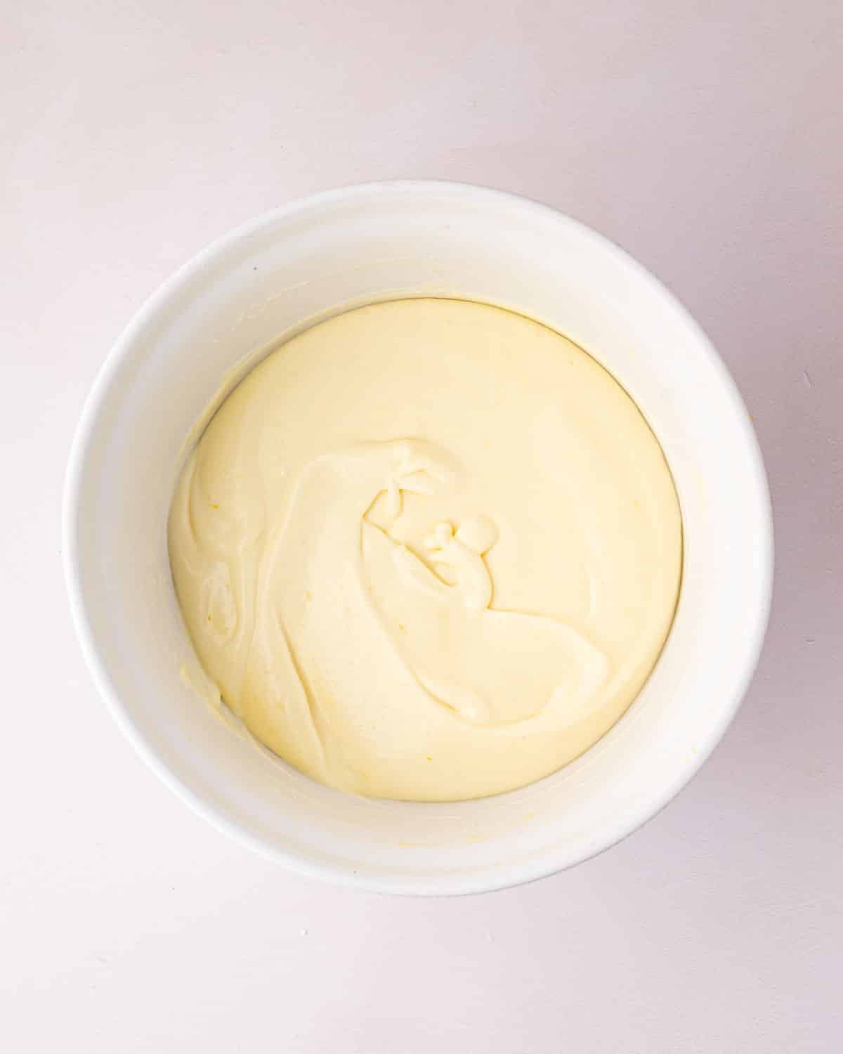 A white bowl with thickened lemon mousse.
