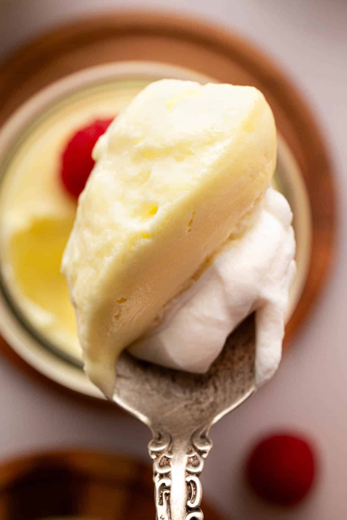 A spoon with lemon mousse and whipped cream.