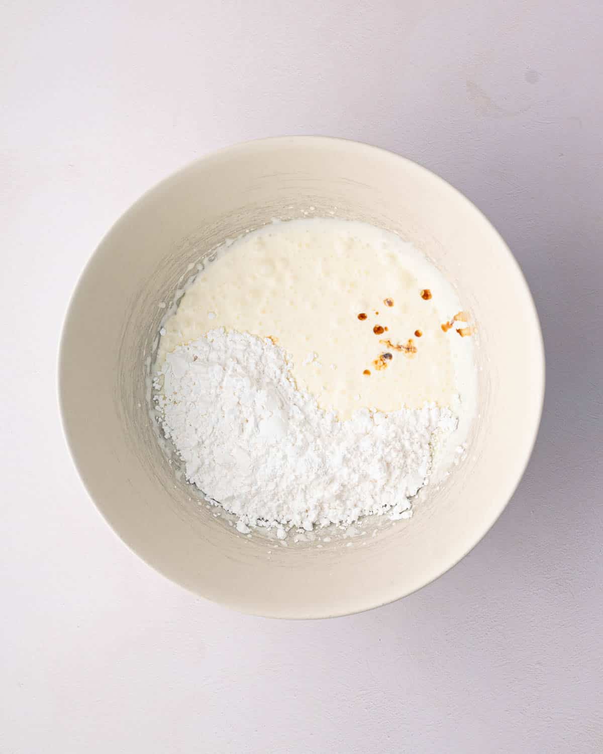 A white bowl with ingredients for mascarpone whipped cream.