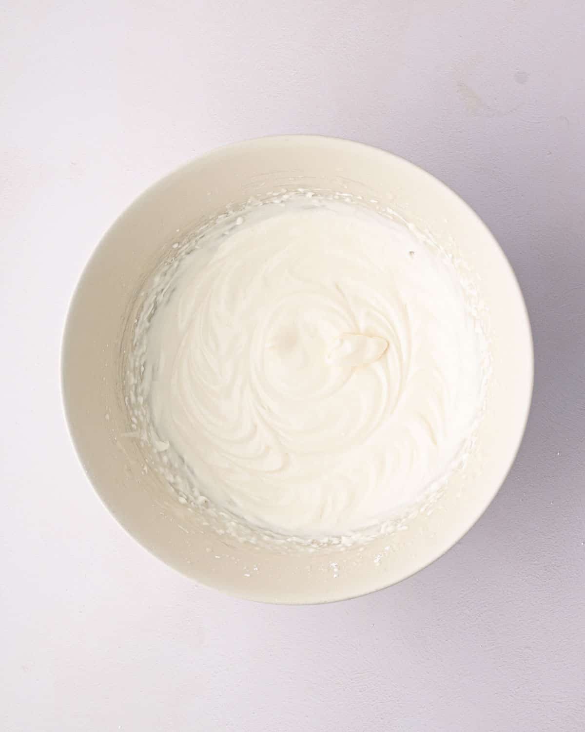 A white bowl with whipped mascarpone whipped cream.