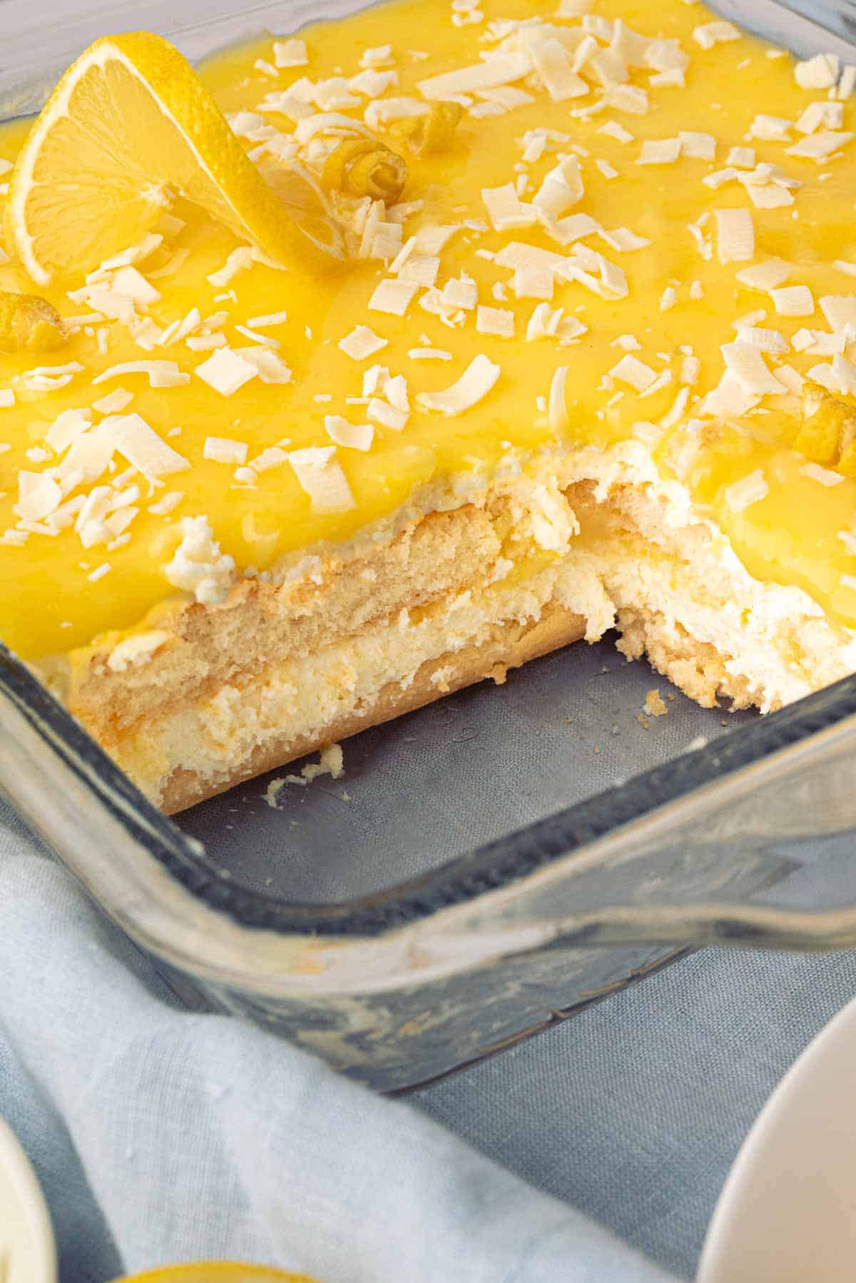 A glass baking dish with a slice out of lemon tiramisu.
