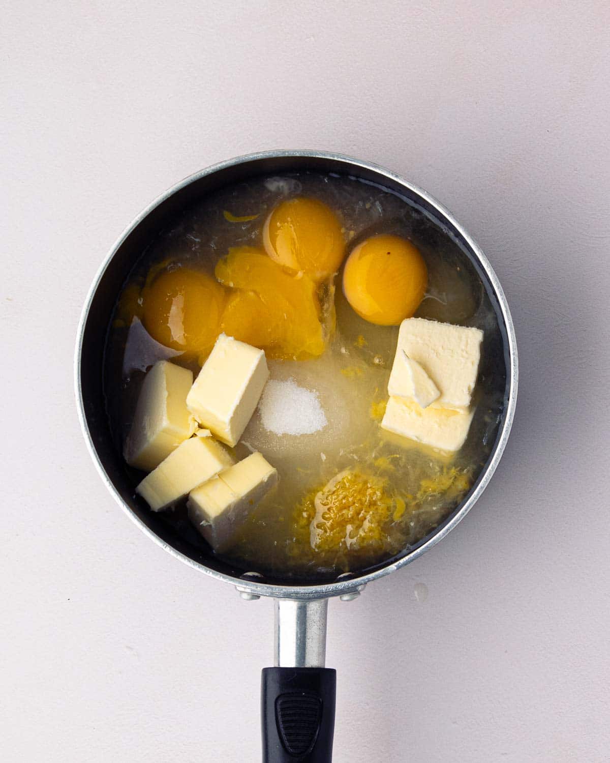 A sauce pan with ingredients for lemon curd.