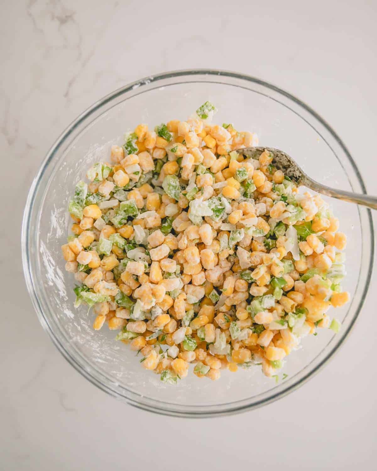 A glass bowl with corn fritter mixture.