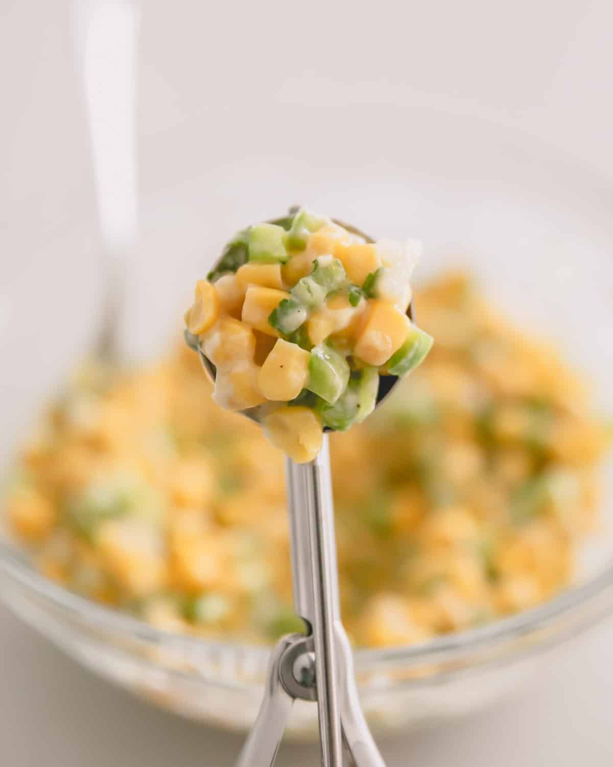 A cookie scoop with the corn fritter mixture.