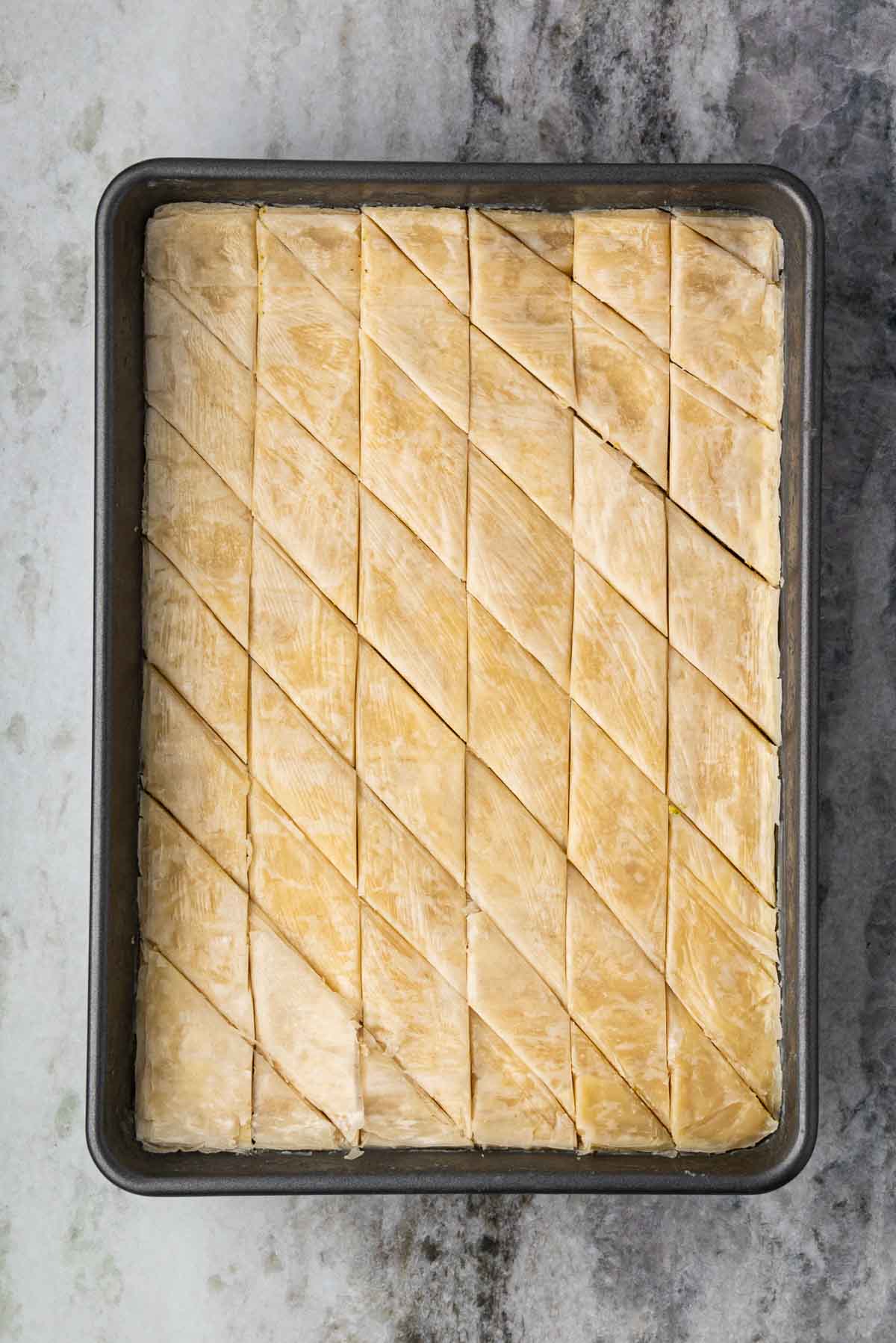 A baking dish with pistachio baklava cut into diamonds.