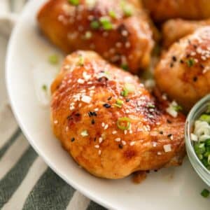 Miso chicken thighs on a white plate with scallions.