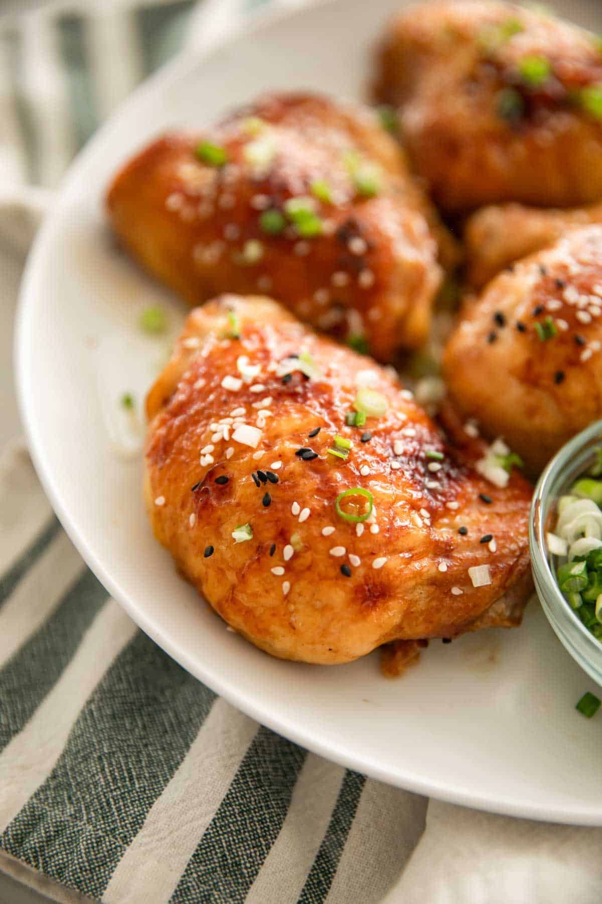 Miso chicken thighs on a white plate with scallions.