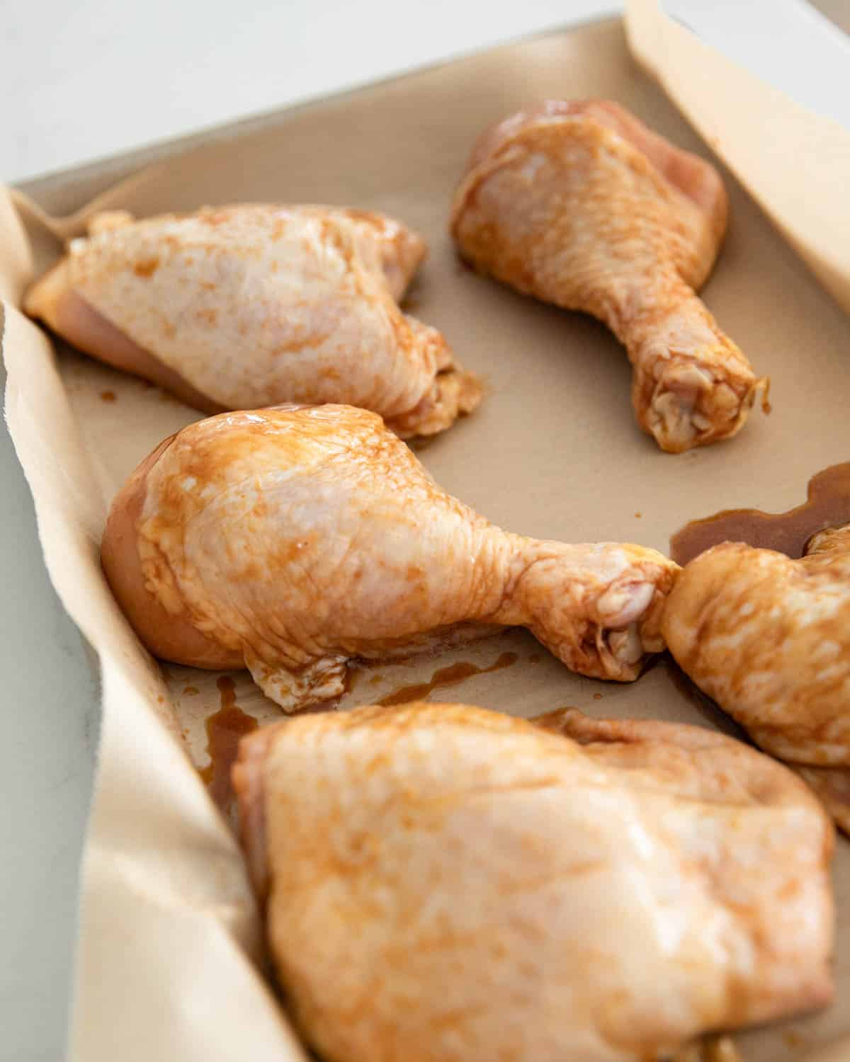 A baking sheet with parchment paper and miso marinated chicken on top of it.