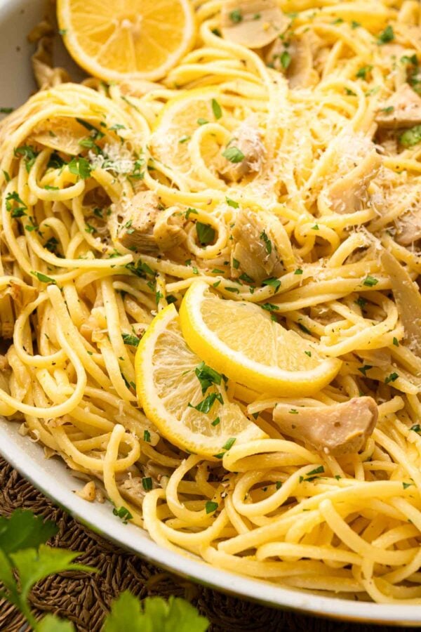 Close up image of lemon artichoke pasta in a white bowl.