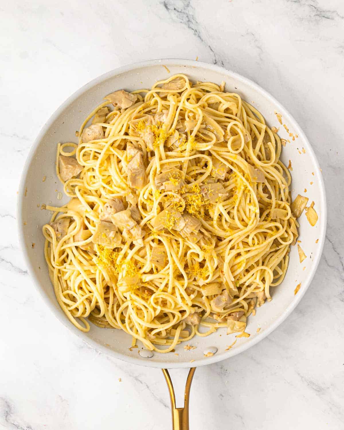 A white skillet lemon artichoke pasta.