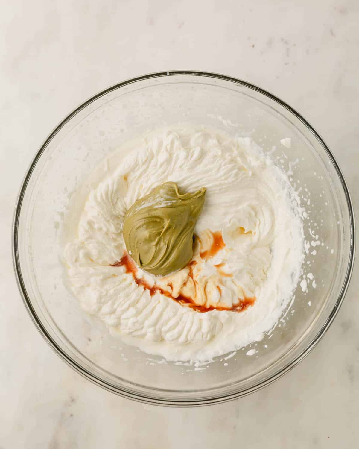 A glass bowl with ingredients for pistachio whipped cream.
