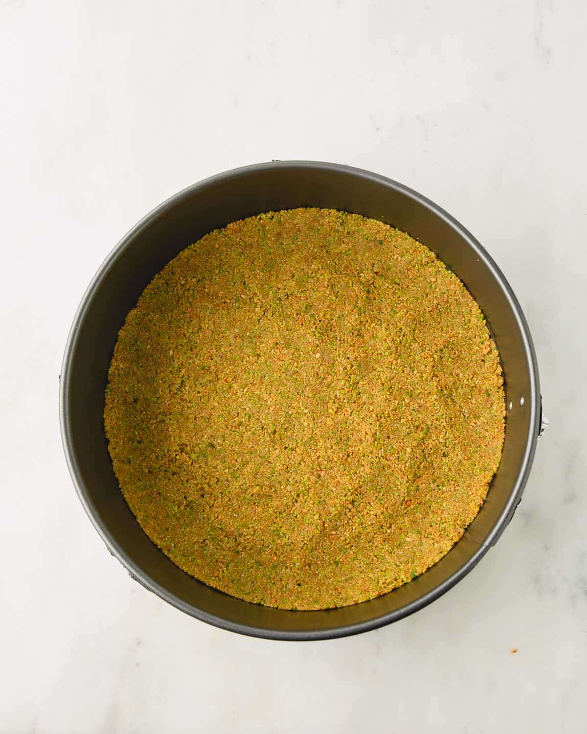 Pistachio graham cracker crust baked in a springform cake pan.