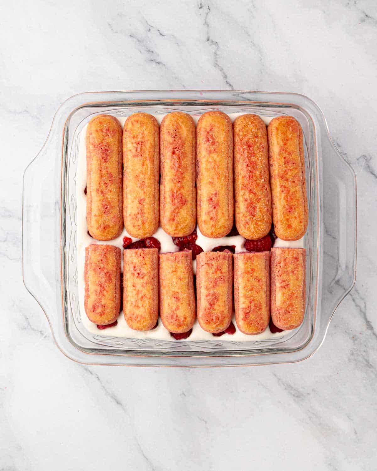 A second layer of dipped ladyfingers is added on top.