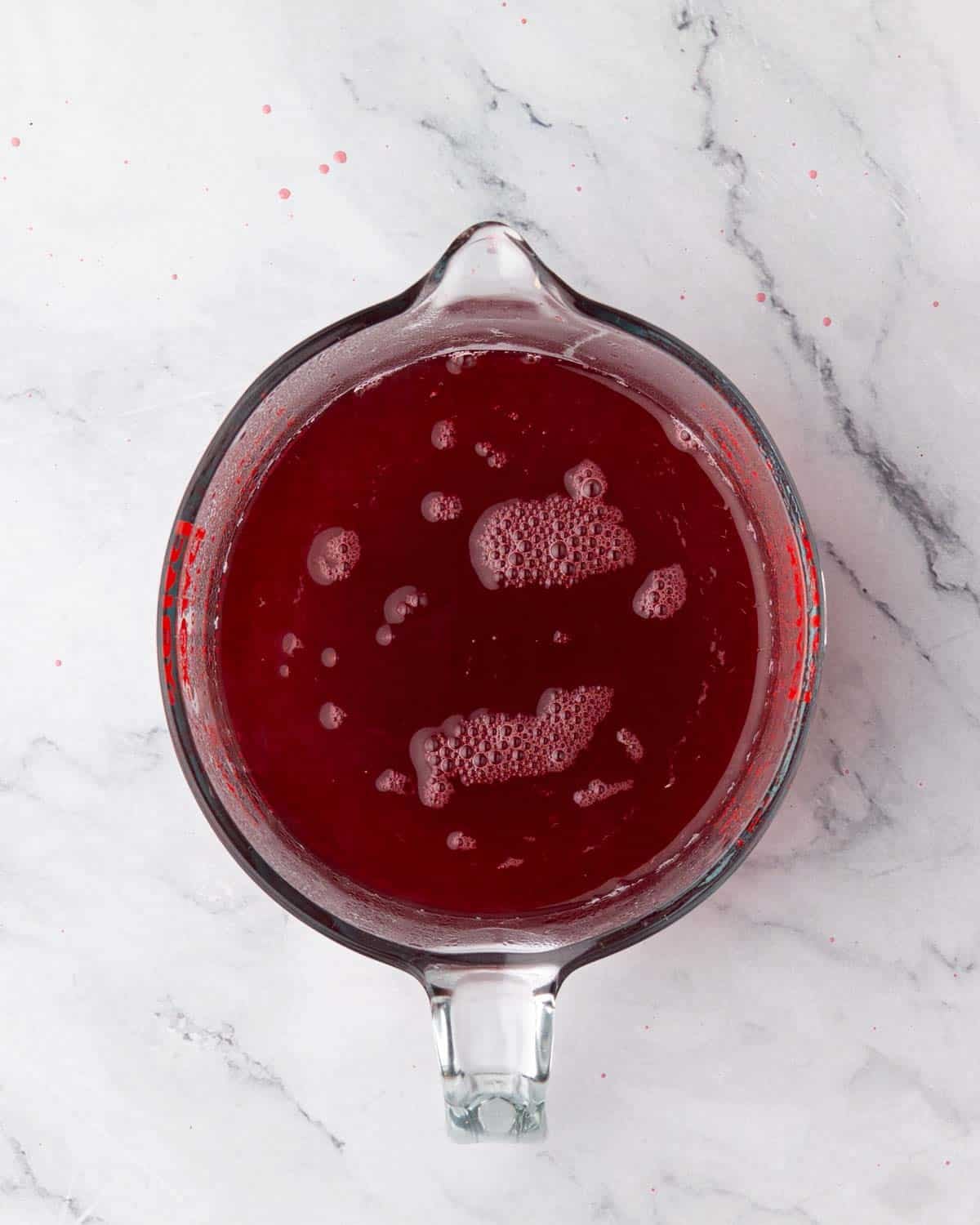 Raspberry simple syrup in a glass measuring cup.