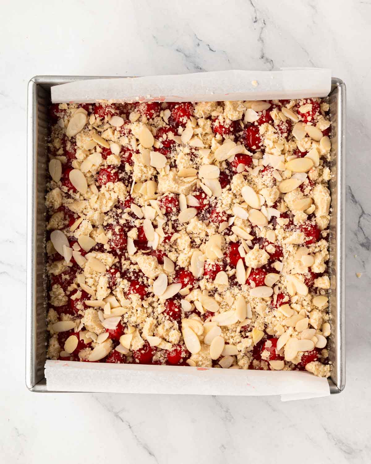 A baking pan with cherry pie bars with streusel and almond topping.