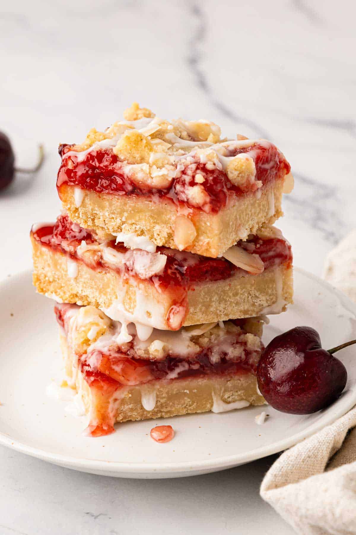 A stack of three cherry pie bars on a white plate.