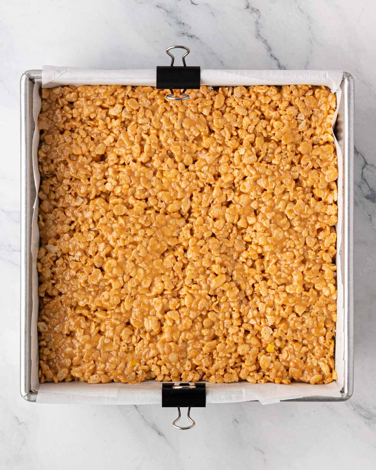 A baking pan with the crunchy base of scotcharoos pressed into the bottom.