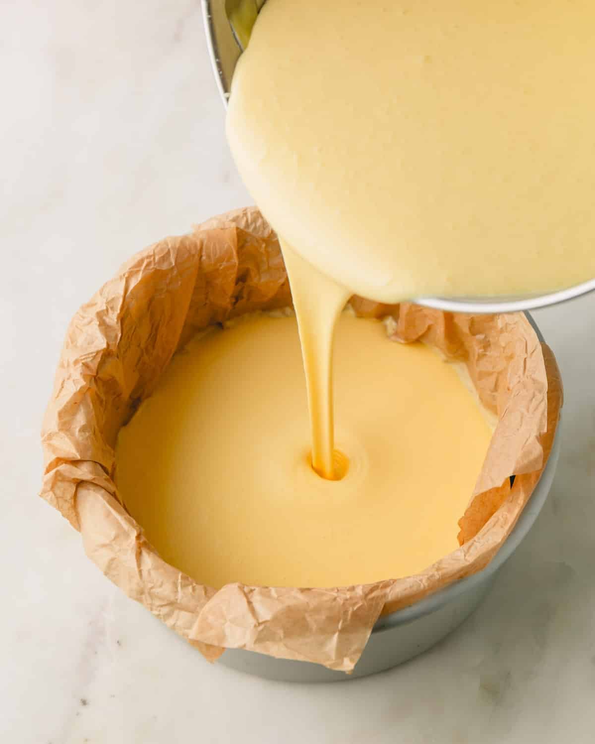 Cheesecake batter is being poured into the prepared pan.