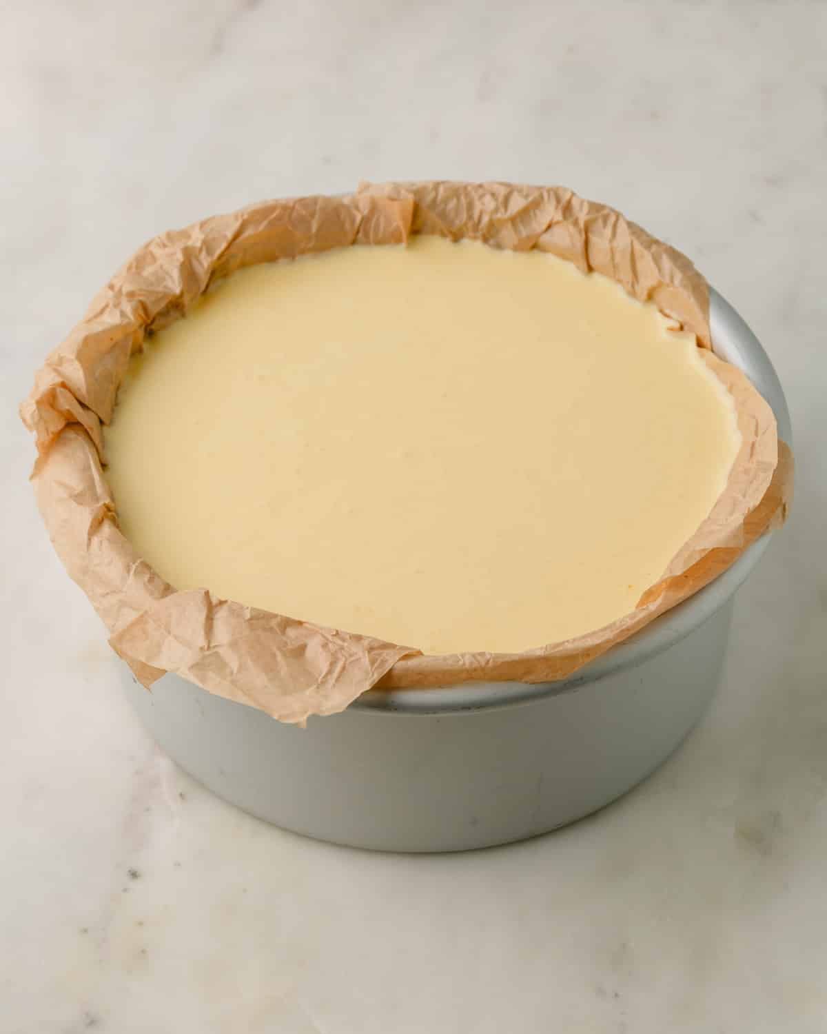 Baking pan lined with parchment paper and filled with the cheesecake batter.