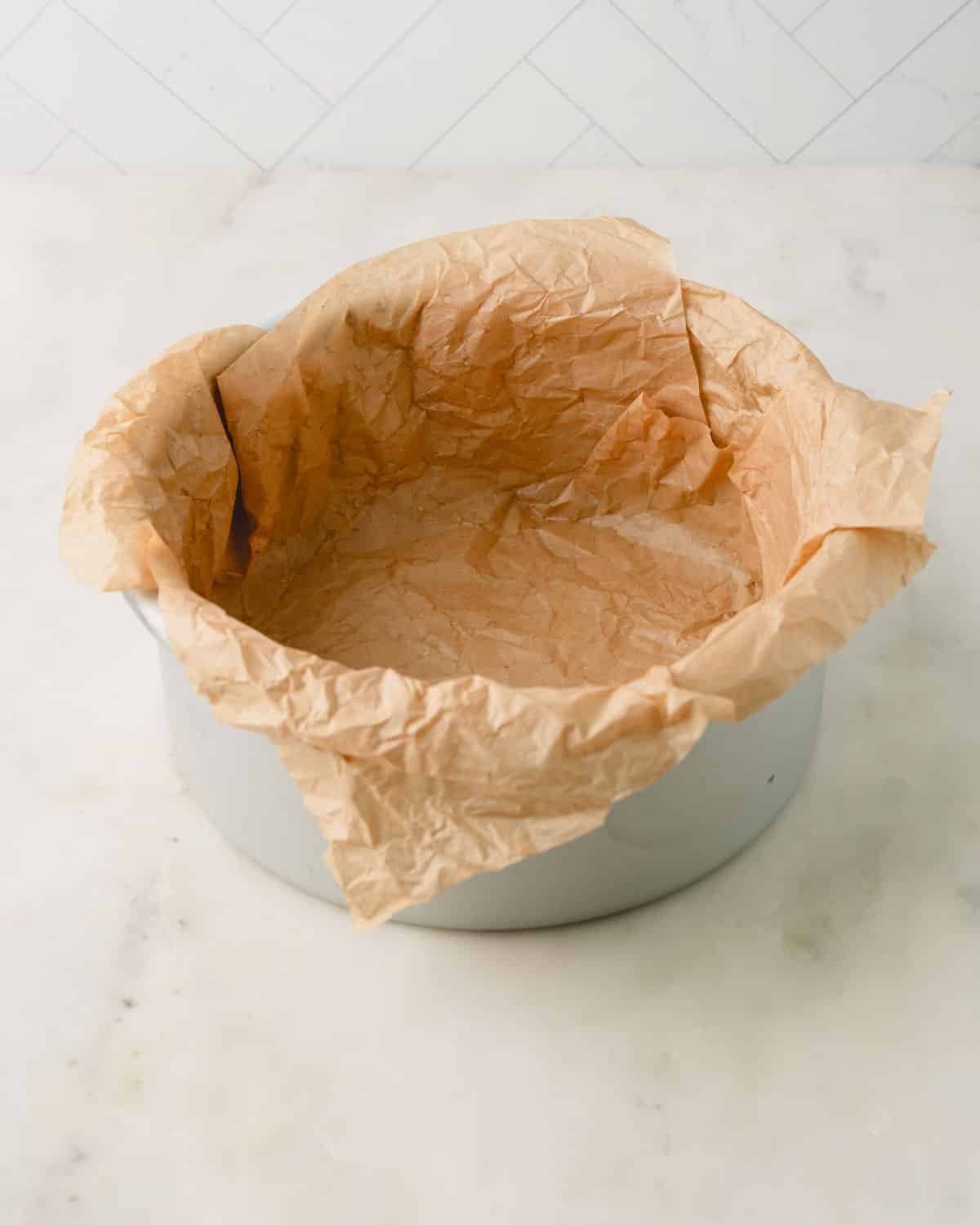 Damp brown parchment paper lined in a round baking pan.