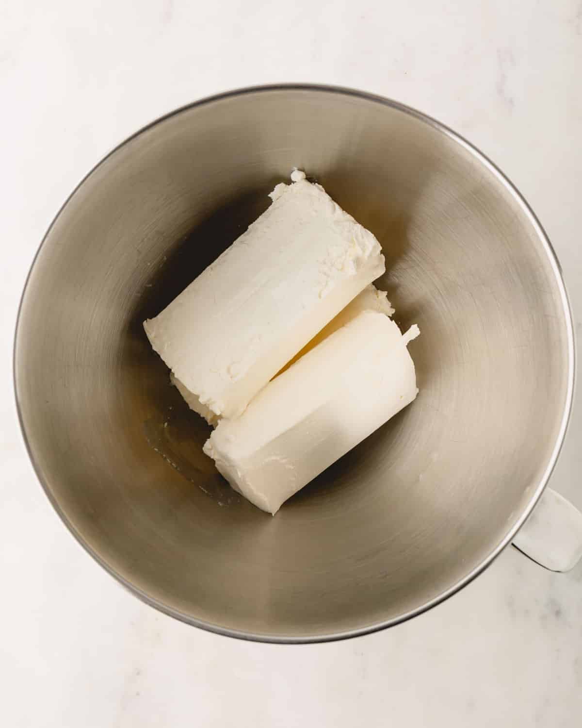 Blocks of cream cheese in a mixing bowl.
