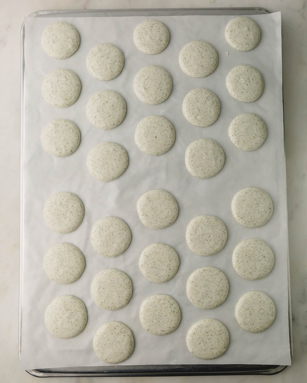 Unbaked macaron shells spread and smoothed out.
