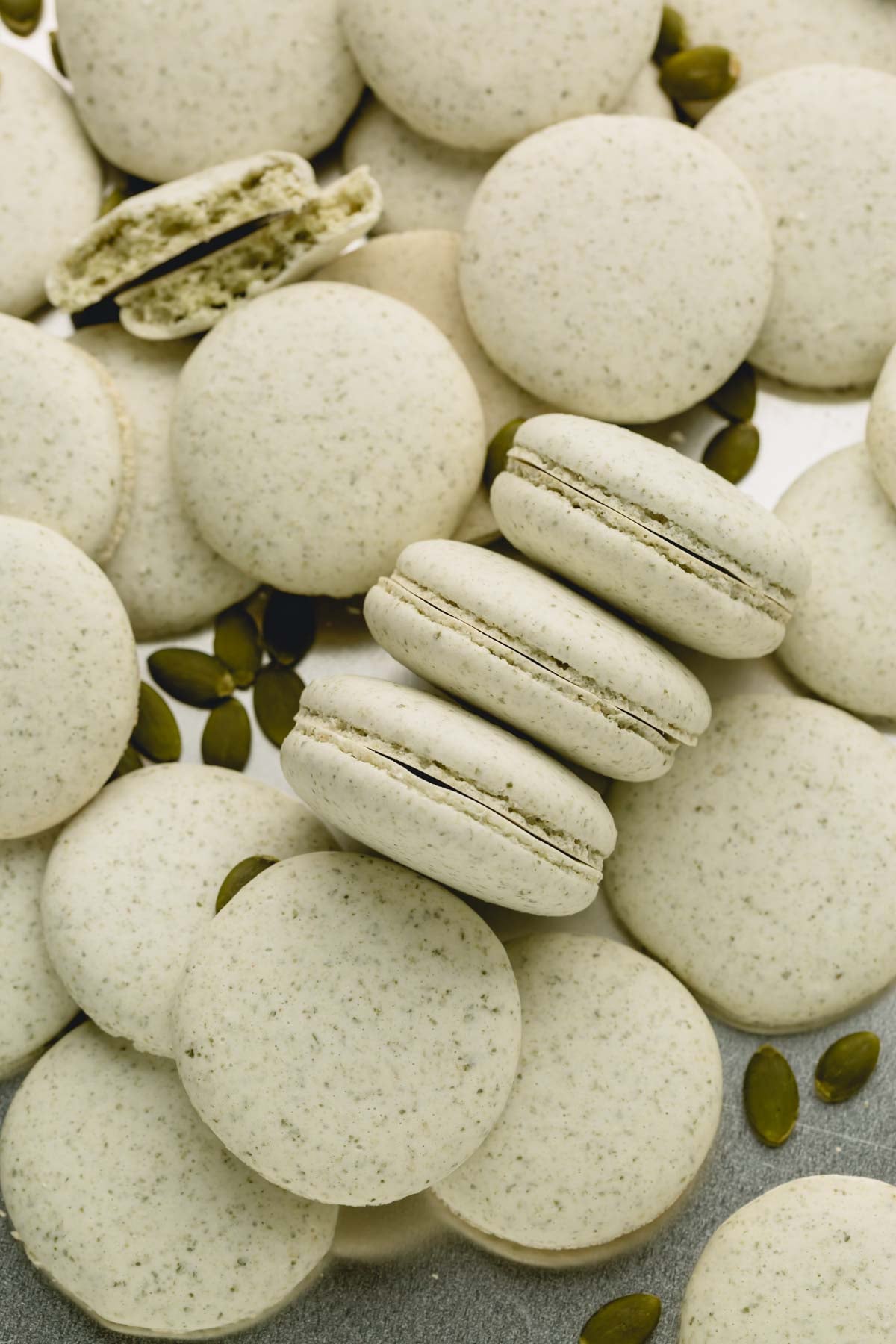 Baked nut free macaron shells with a few sunflower seeds spread around.