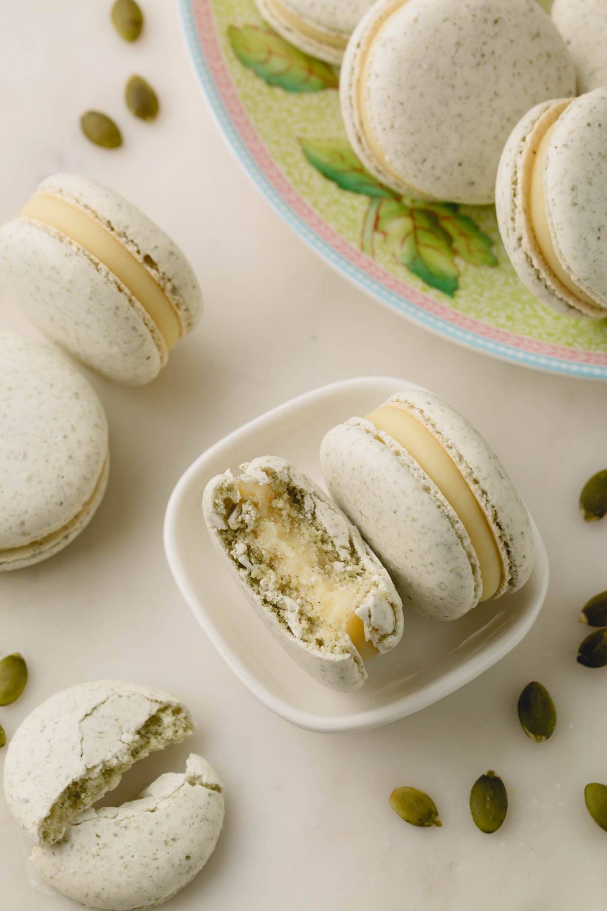 Nut free macarons with sunflower seeds with scattered sunflower seeds and one macaron is bitten.