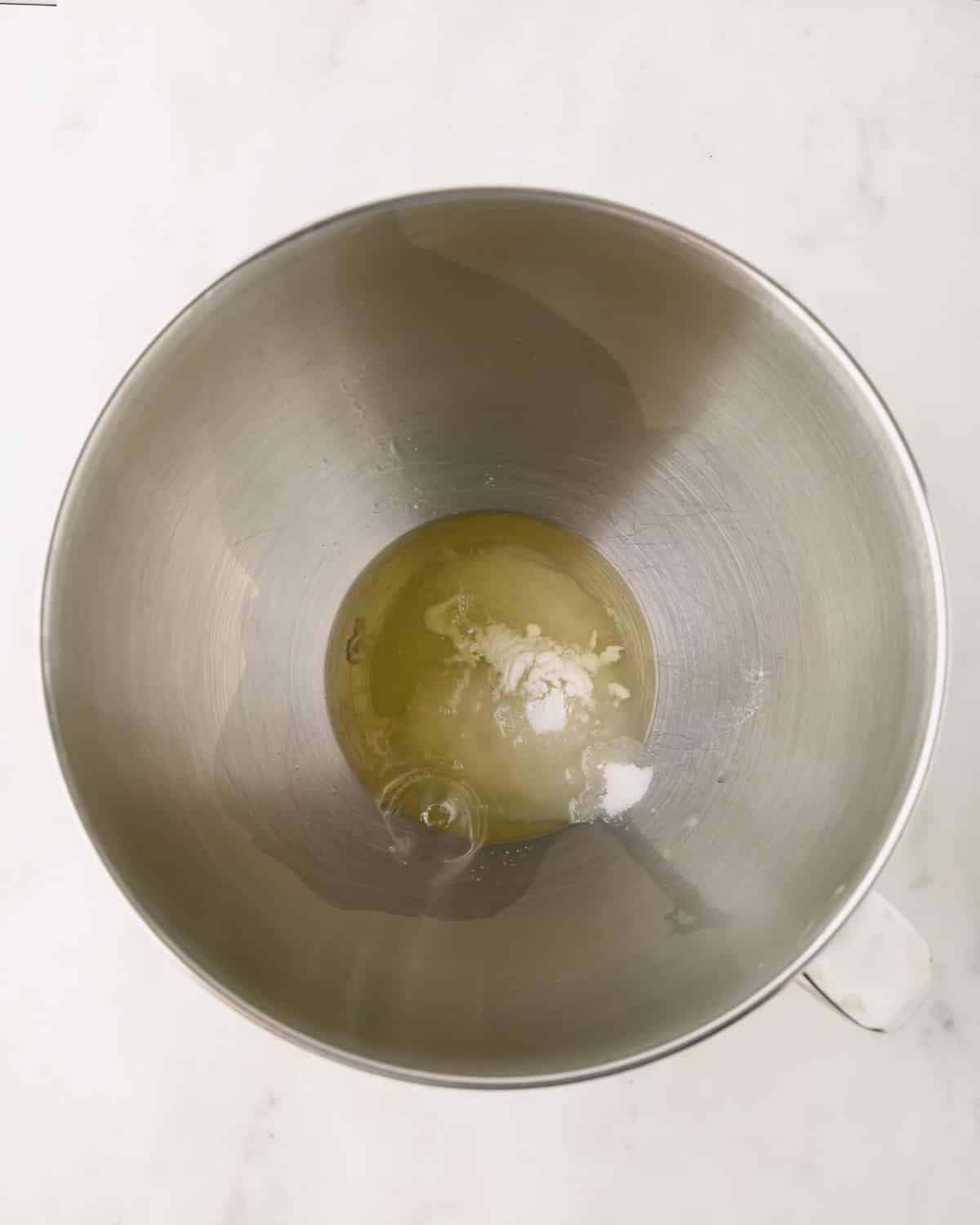 Egg whites with salt and cream of tartar in a mixing bowl of a stand mixer.